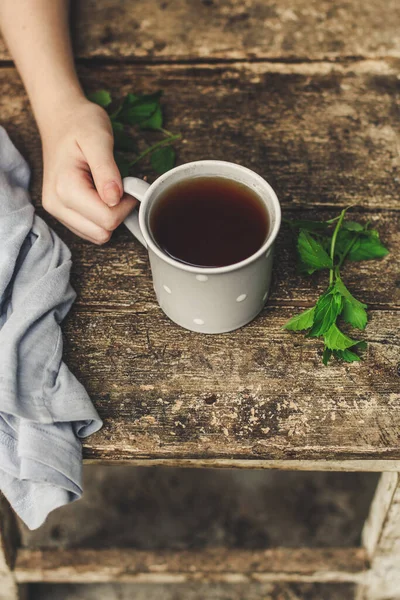 woman holding cup of tea and coffee on wooden background