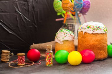 Paskalya pastalarının ve renkli yumurtaların koyu arkaplanda yakın plan görüntüsü.