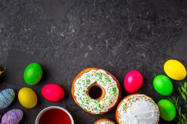 Paskalya pastalarının ve renkli yumurtaların koyu arkaplanda yakın plan görüntüsü.