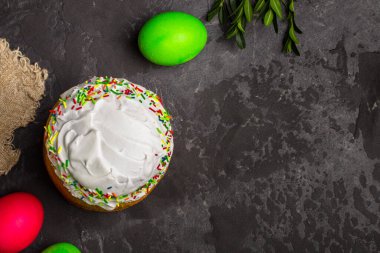 Paskalya pastalarının ve renkli yumurtaların koyu arkaplanda yakın plan görüntüsü.