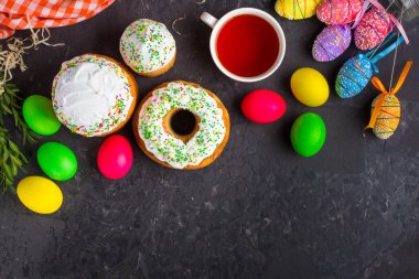 Paskalya pastalarının ve renkli yumurtaların koyu arkaplanda yakın plan görüntüsü.