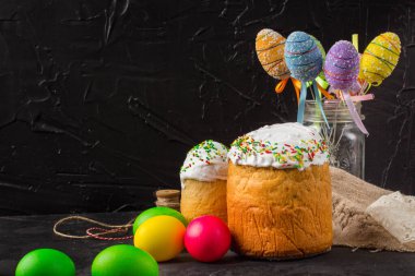 Paskalya pastalarının ve renkli yumurtaların koyu arkaplanda yakın plan görüntüsü.