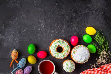 Paskalya pastalarının ve renkli yumurtaların koyu arkaplanda yakın plan görüntüsü.