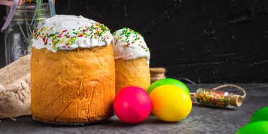 Paskalya pastalarının ve renkli yumurtaların koyu arkaplanda yakın plan görüntüsü.