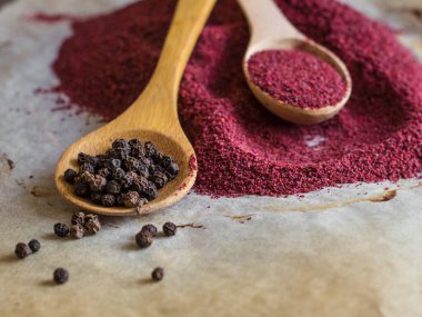 Siyah arka planda tahta kaşıkta kırmızı ve beyaz biber.