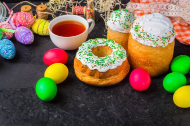 Paskalya pastalarının ve renkli yumurtaların koyu arkaplanda yakın plan görüntüsü.