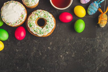 Paskalya pastalarının ve renkli yumurtaların koyu arkaplanda yakın plan görüntüsü.