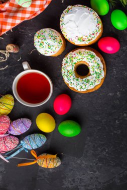 Paskalya pastalarının ve renkli yumurtaların koyu arkaplanda yakın plan görüntüsü.