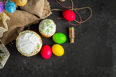 Paskalya pastalarının ve renkli yumurtaların koyu arkaplanda yakın plan görüntüsü.