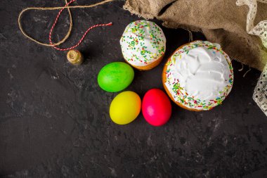 Paskalya pastalarının ve renkli yumurtaların koyu arkaplanda yakın plan görüntüsü.