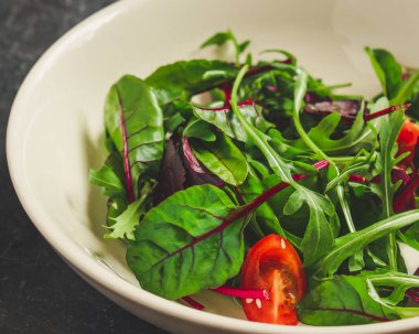 Yeşiller tabakta domateslerle karışır.