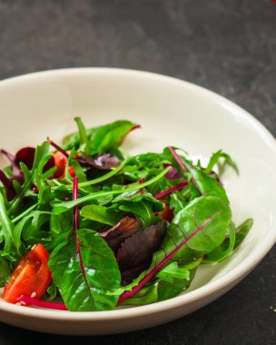 Yeşiller tabakta domateslerle karışır.