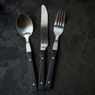 çatal, bıçak ve kaşık koyu taş arka planda