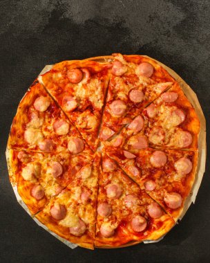 Siyah arka planda sosisli, peynirli ve domates soslu pizza. 