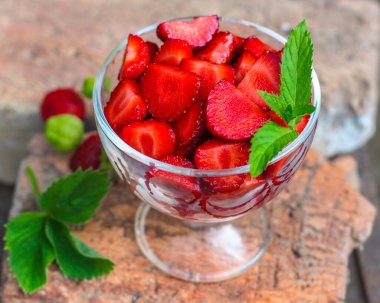 Arka planda cam bir kavanozda taze çilekler..