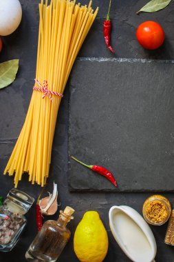 Karanlık arka planda yemek pişirmek için malzemeli spagetti.