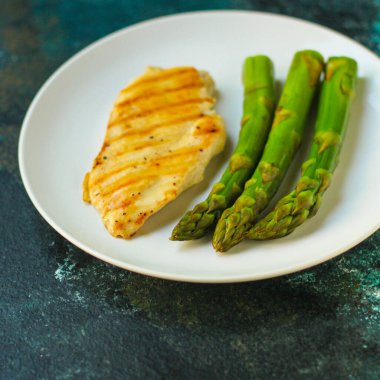 Beyaz tabakta kuşkonmaz ve ızgara somon, yakın çekim.