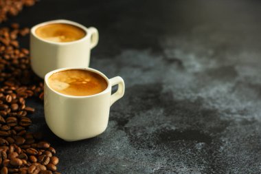 Koyu arkaplanda bir fincan kahve ve fasulye.