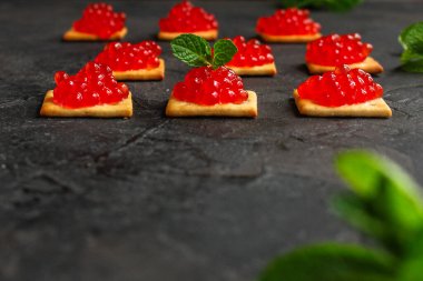 Krakerlerde kırmızı havyar ve siyah arka plan.