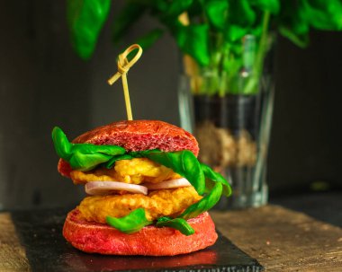 Sebzeli ve peynirli lezzetli bir burgerin yakın plan çekimi.