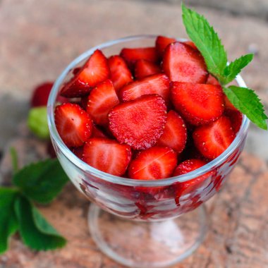 Arka planda cam bir kavanozda taze çilekler..