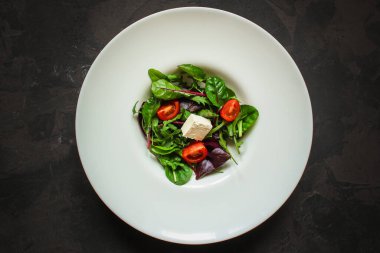 Domates ve peynirle karışık yeşiller.