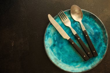 Siyah arka planda boş bir tabak ve çatal. en üstteki görünüm.