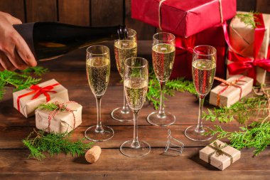 Ahşap bir arka planda iki kadeh şampanya ve noel hediyesi..