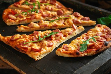Salamlı, peynirli ve fesleğenli pizza.