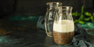 Bir bardak yeşil çay, chia tohumu ve koyu arkaplanda bir fincan kahve..