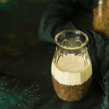 Tahta bir masada bir bardak süt ve ayçiçeği çekirdeği.