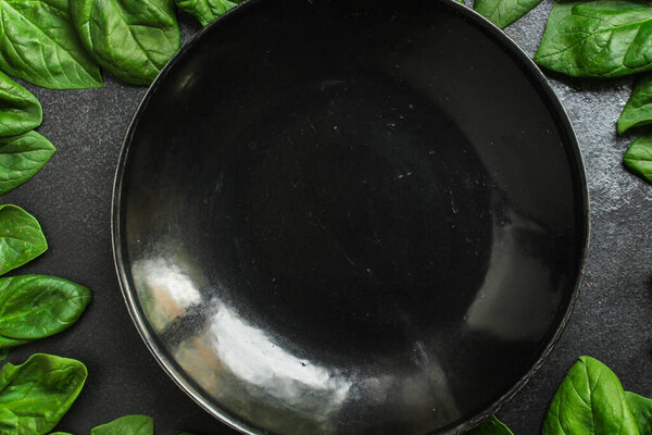 spinach leaves near plate on dark background