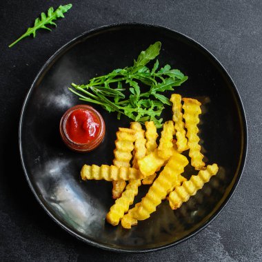 Domates soslu kızarmış patates cipsi ve siyah arka planda ketçap.