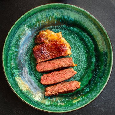 Soslu ızgara biftek ve siyah arka planda baharatlar. 