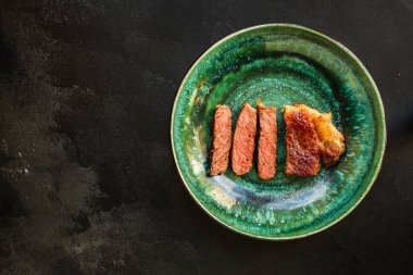 Soslu ızgara biftek ve siyah arka planda baharatlar. 