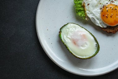 Siyah arka planda avokadolu sahanda yumurta manzarası. en üstteki görünüm.