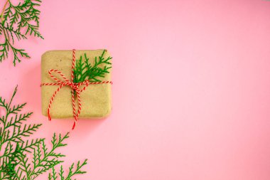Parlak arkaplanda kurdeleli ve yeşil dallı hediye kutusunun üst görünümü.