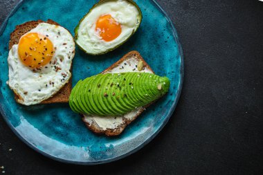 Siyah arka planda avokadolu sahanda yumurta manzarası. en üstteki görünüm.