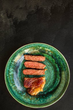 Soslu ızgara biftek ve siyah arka planda baharatlar. 