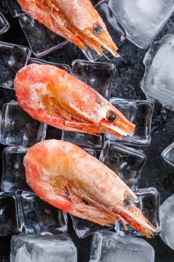 Koyu yüzeyinde buz küpleri olan karideslerin üst görüntüsü