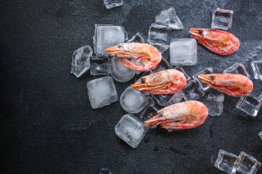 Koyu yüzeyinde buz küpleri olan karideslerin üst görüntüsü