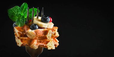 Koyu arkaplanda böğürtlen ve nane yapraklı Belçika waffleları