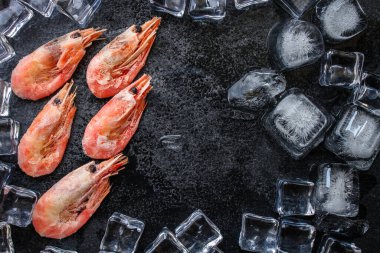 Koyu yüzeyinde buz küpleri olan karideslerin üst görüntüsü