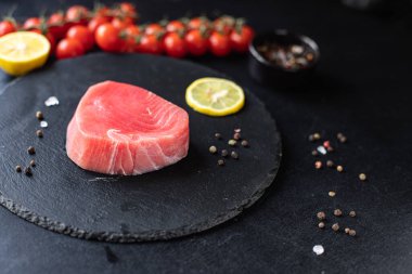 Siyah arka planda sebzeli çiğ somon filetosu. 