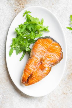 Arugula soslu somon bifteği ve tabakta salata yaprakları. en üstteki görünüm.