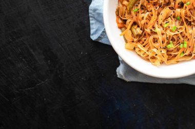 Kızarmış erişteyi sebze ve baharatla karıştır, yakından bak.