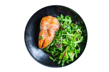 Arugula soslu somon bifteği ve tabakta salata yaprakları. en üstteki görünüm.