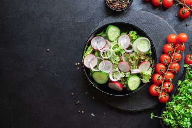 Taze sebzeli salata ve siyah arkaplanda roka. 