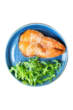 Arugula soslu somon bifteği ve tabakta salata yaprakları. en üstteki görünüm.