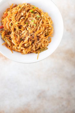 Kızarmış erişteyi sebze ve baharatla karıştır, yakından bak.